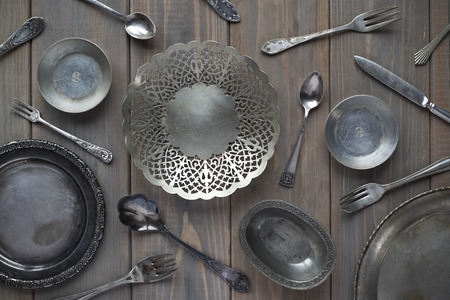 vintage spoons, forks, knives and metal plates on a gray wooden backgroundの写真素材