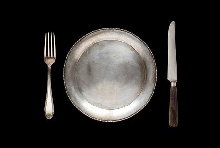 Metal antique plate, knife and fork  isolated on a black backgroundの写真素材