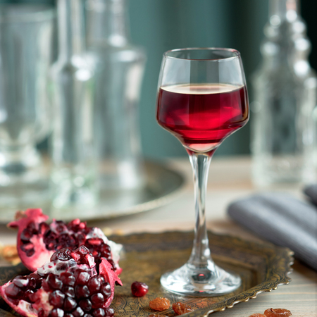 A glass of pomegranate liqueur on the table with grenadesの写真素材