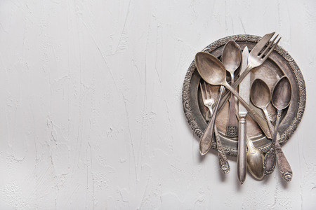 Vintage silver spoons, forks and knife on vintage white background. Copy spaceの写真素材