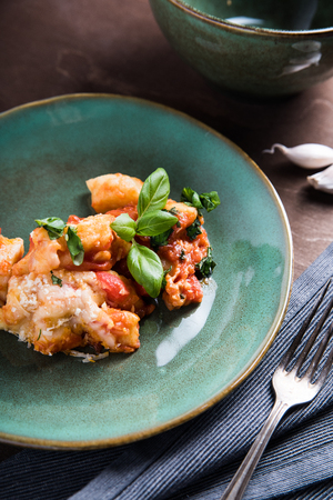Italian food. Gnocchi with cheese and basil in handmade on a green plate on the old wooden table, near the vintage fork and knifeの写真素材