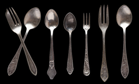 Beautiful old vintage knifes and spoons isolated on black background. Top view. Retro silverware.の写真素材