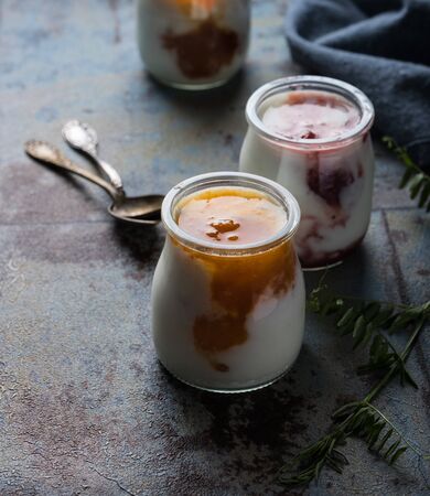 Three portions of fresh natural homemade organic yogurt in a glass jar on a vintage backgroundの写真素材