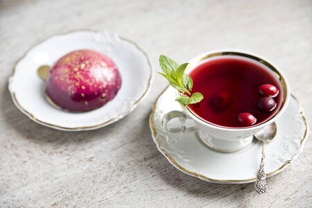 Red tea hibiscus in a vintage cup, antique spoon, cake, raspberry. Copy spaceの写真素材