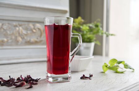 Red hibiscus tea in a transparent glass against the background of a vintage wallの写真素材