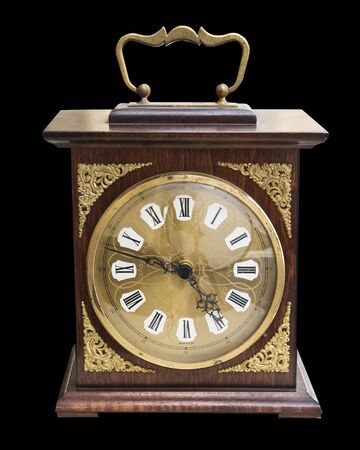 Vintage beautiful clock with a wooden case and gold jewelry isolated on blackの写真素材
