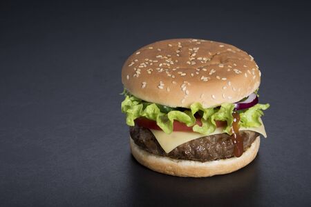 Hamburger with a double serving of meat, tomatoes, salad, onions on a wooden board in a restaurant.Copy spaceの写真素材