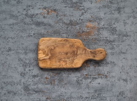 Wooden cutting board on gray concrete background. Table top view and copy space for text. Restaurant menu, recipe, food background mock up. Copy space.の写真素材