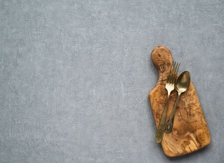 Wooden cutting board, vintage boat and fork on gray concrete background. Table top view and copy space for text. Restaurant menu, recipe, food background mock up. Copy space.の写真素材