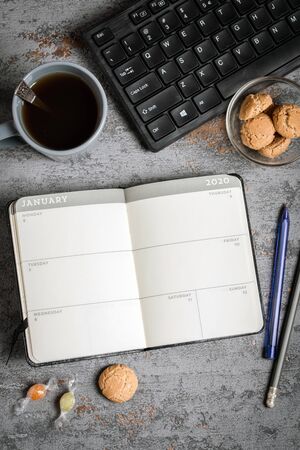 daily planner for 2020, open, lies on the table, tea, cookies, keyboard, candyの写真素材