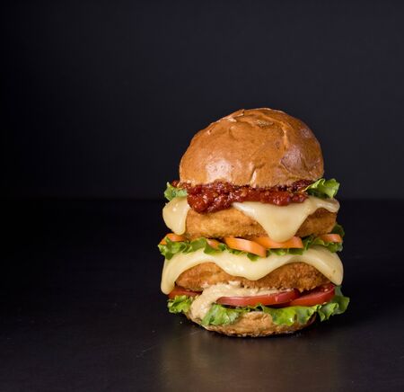 Hamburger with a double serving of meat, tomatoes, salad, onions on a wooden board in a restaurant.Copy spaceの写真素材