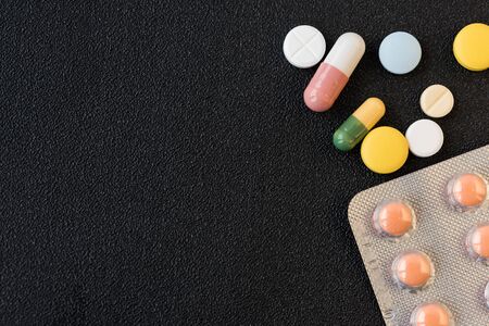 Pile of medicines pills closeup on black texture background. Concept of Health Care. Copy space.の写真素材