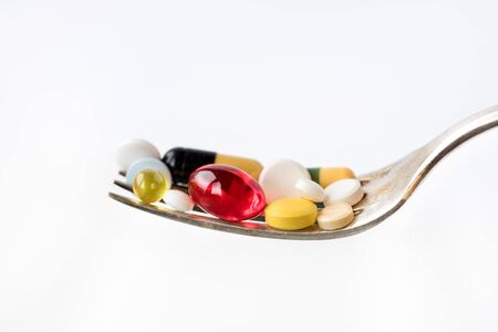 Assorted pharmaceutical medicine pills, tablets and capsules in a spoon on white background. Healthcare concept. Copy space.の写真素材
