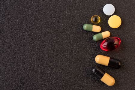 Pile of medicines pills closeup on black texture background. Concept of Health Care. Copy space.の写真素材