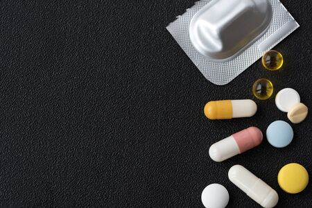 Pile of medicines pills closeup on black texture background. Concept of Health Care. Copy space.の写真素材