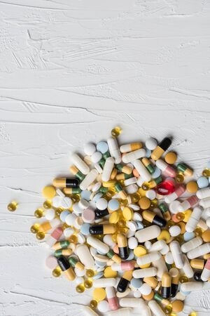 Pile of medicines pills closeup on white texture background. Concept of Health Care. Copy space.の写真素材