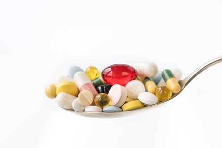 Assorted pharmaceutical medicine pills, tablets and capsules in a spoon on white background. Healthcare concept. Copy space.の写真素材