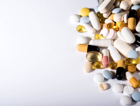 Medicines and Pills on a white plate. A pile of multi-colored tablets disguised as food on a plate with cutlery on a white plate. Isolated on white background.の写真素材