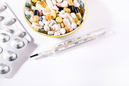 Pills and thermometer on a white background, the concept of a flu epidemic. Copy space.
