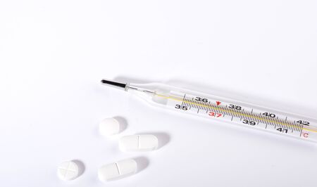 Pills and thermometer on a white background, the concept of a flu epidemic. Copy space.