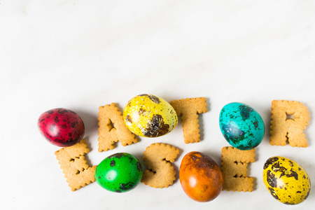 Color quail eggs with word 'Easter' of cookies on the white background with copy spaceの写真素材