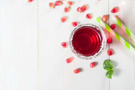 Pomegranate drink in glass with sugar decoration on white wooden background with copy space, top viewの写真素材