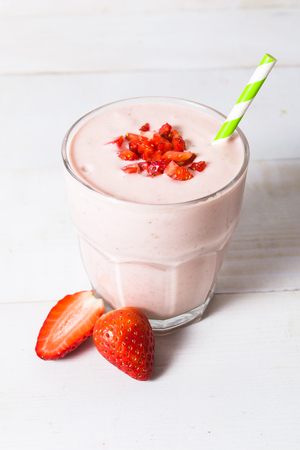 Fresh strawberry yogurt smoothie with berries on white wooden tableの写真素材
