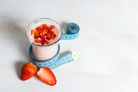 Strawberry yogurt smoothie with measure tape on white wooden backgroundの写真素材