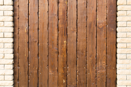 Brown wooden vertical panel plank wall background with columns of brickの写真素材