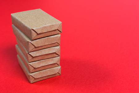 Stack of five wrapped craft boxes on red background with copy space
