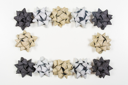 Silver, golden and black holiday bows like frame on white background with copy spaceの写真素材