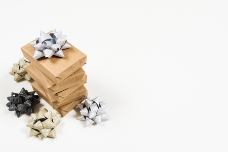 Stack of holiday wrapped gifts packing craft paper with holiday bows on white background with copy spaceの写真素材