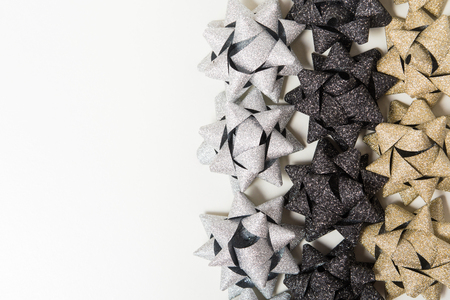 Silver, golden and black holiday bows on white background with copy spaceの写真素材