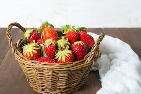Basket of strawberry on brown wooden table with white backgroundの写真素材