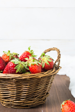 Basket of strawberry over brown wooden table and white background with copy space, vertical shotの写真素材