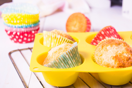 Muffins in silicon form in baking pan on white wooden tableの写真素材