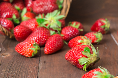Fresh strawberry falled out of basket over brown wooden backgroundの写真素材