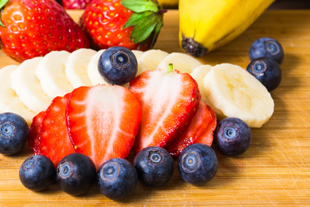 Closeup slices of blueberry, strawberry and banana on wooden boardの写真素材