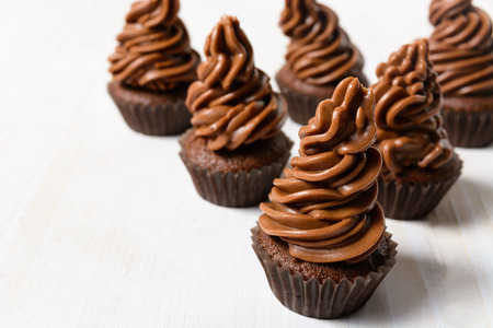 Some chocolate cupcakes with cocoa cream on white wooden table with copy spaceの写真素材