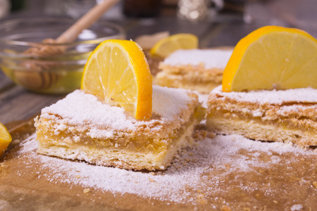 Lemon pie with sugar powder and lemon decoration on the baking paper and wooden backgroundの写真素材