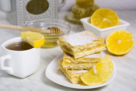 Three pieces of lemon pie with fresh lemon and cup of tea and teapot on the backgroundの写真素材