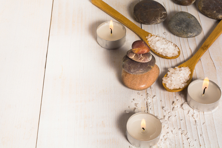 Group of stones with sea salt and candles on the white wooden background with copy spaceの写真素材