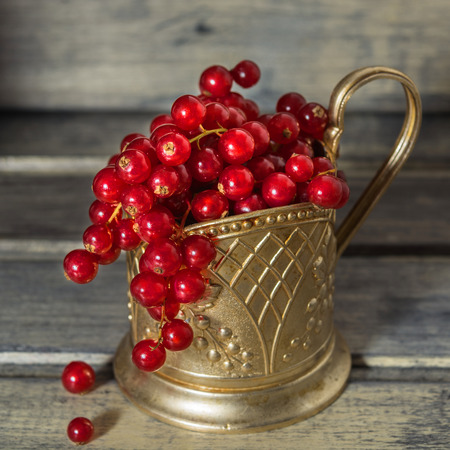 Red currant in the metal glass-holder on the wooden backgroundの写真素材