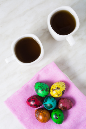 Easter breakfast with color quail eggs and two cup of tea on the white backgroundの写真素材