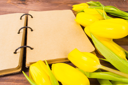 Open vintage notebook or diary and yellow tulips on the white wooden tableの写真素材
