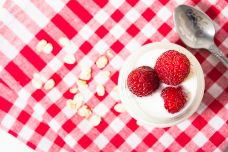 Overnight oatmeal with yogurt and raspberry on the checkered tissue on the white background with...
