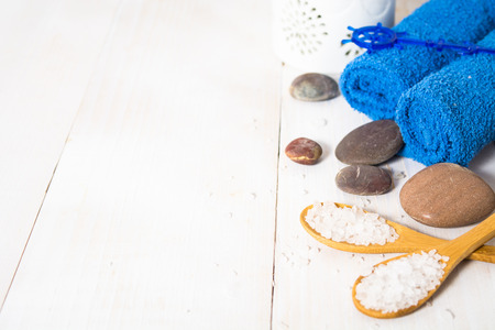Spa still life with stones, salt, aroma and towels on the white wooden table with copy spaceの写真素材