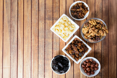 Different dried fruits in white bowls over brown wooden background with copy spaceの写真素材