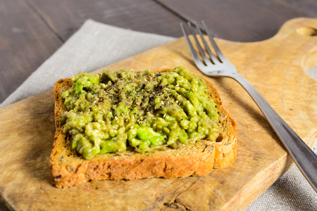 Avocado toast on wooden board with forkの写真素材