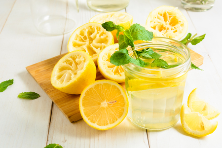 Lemonade with mint and squeezed lemons on board over white wooden backgroundの写真素材
